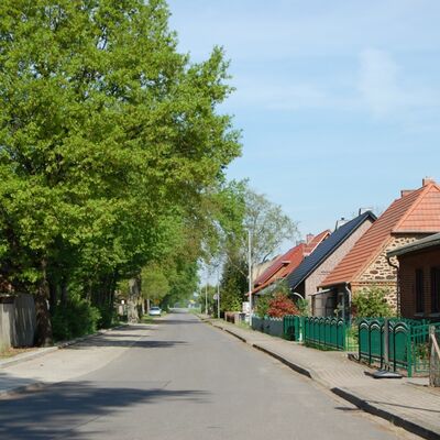 Bild vergrößern: Auf diesem Bild blickt man entlang der Weselsdorfer Dorfstrae. Links ragen Bume in die Hhe und rechts sind die Huser, beginnend mit dem Gasthof "Zum Rosengarten" zu sehen.